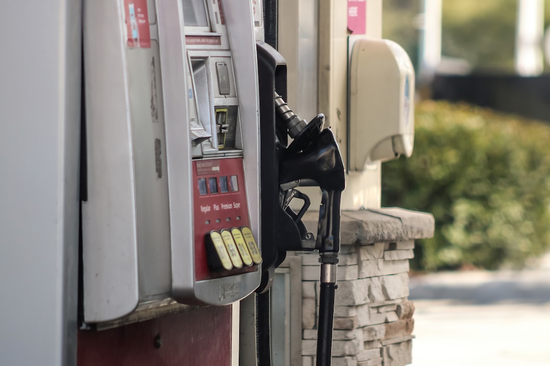 A gas station pump displaying fuel prices as a driver fills up their vehicle's tank
