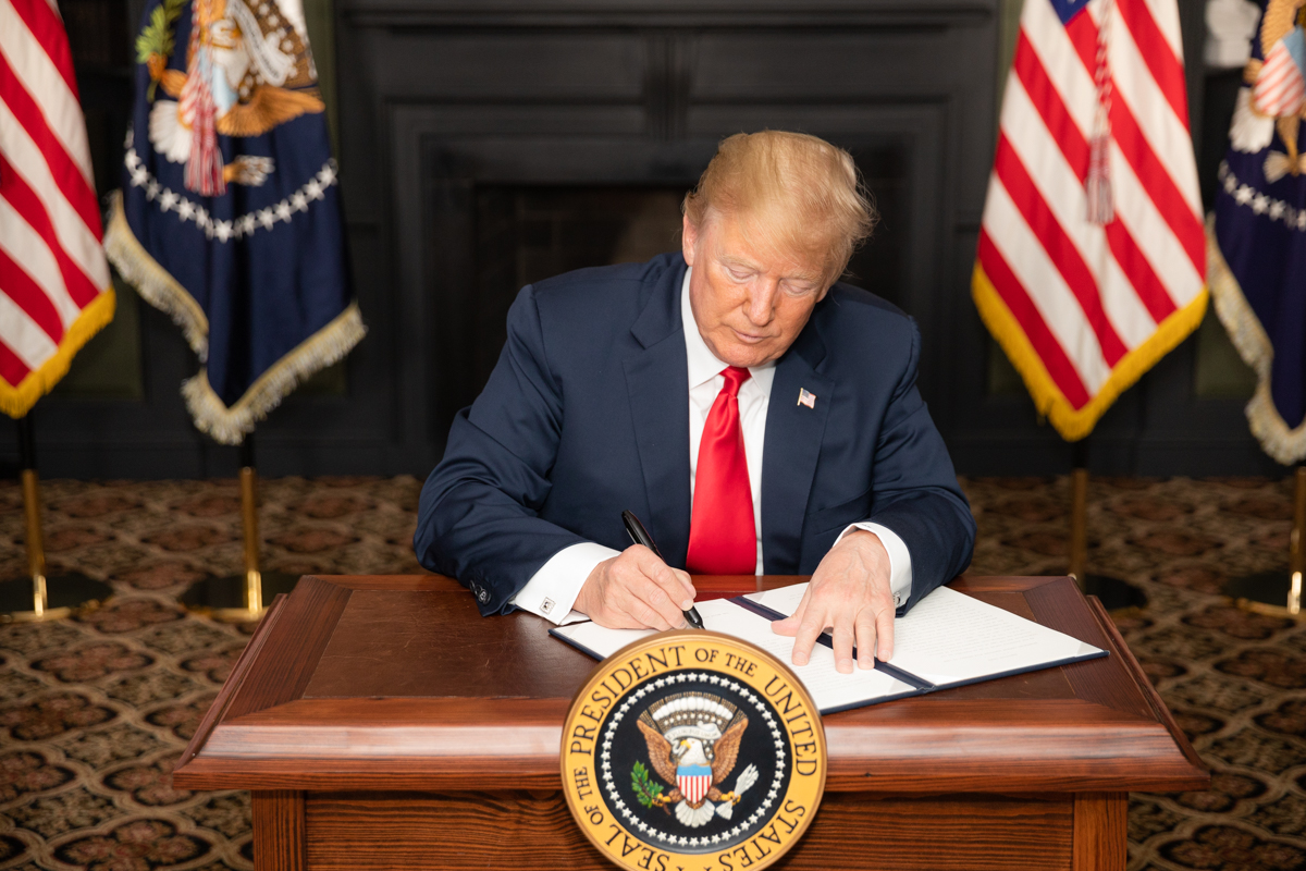 President Donald Trump speaking at a podium during a press event on Iran policy