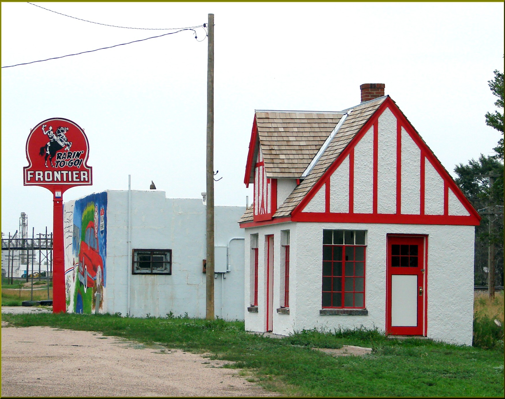 A weathered farm and small-town gas station in rural America, with fuel price signs visible under an overcast sky